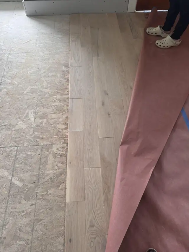 Light oak floor boards being laid over the subfloor during a Garibay Flooring Co installation