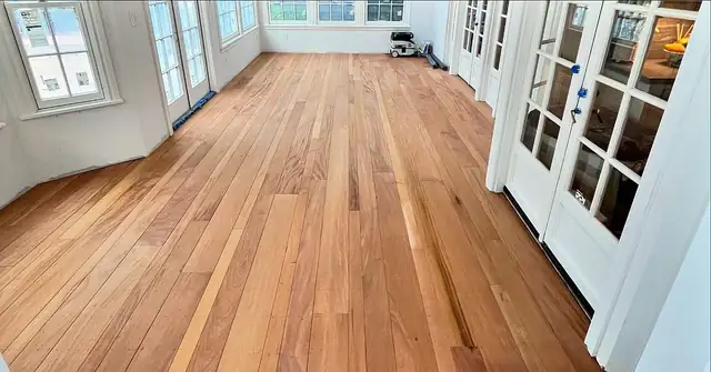 Warm amber wide-plank wood floor in a bright room with French doors
